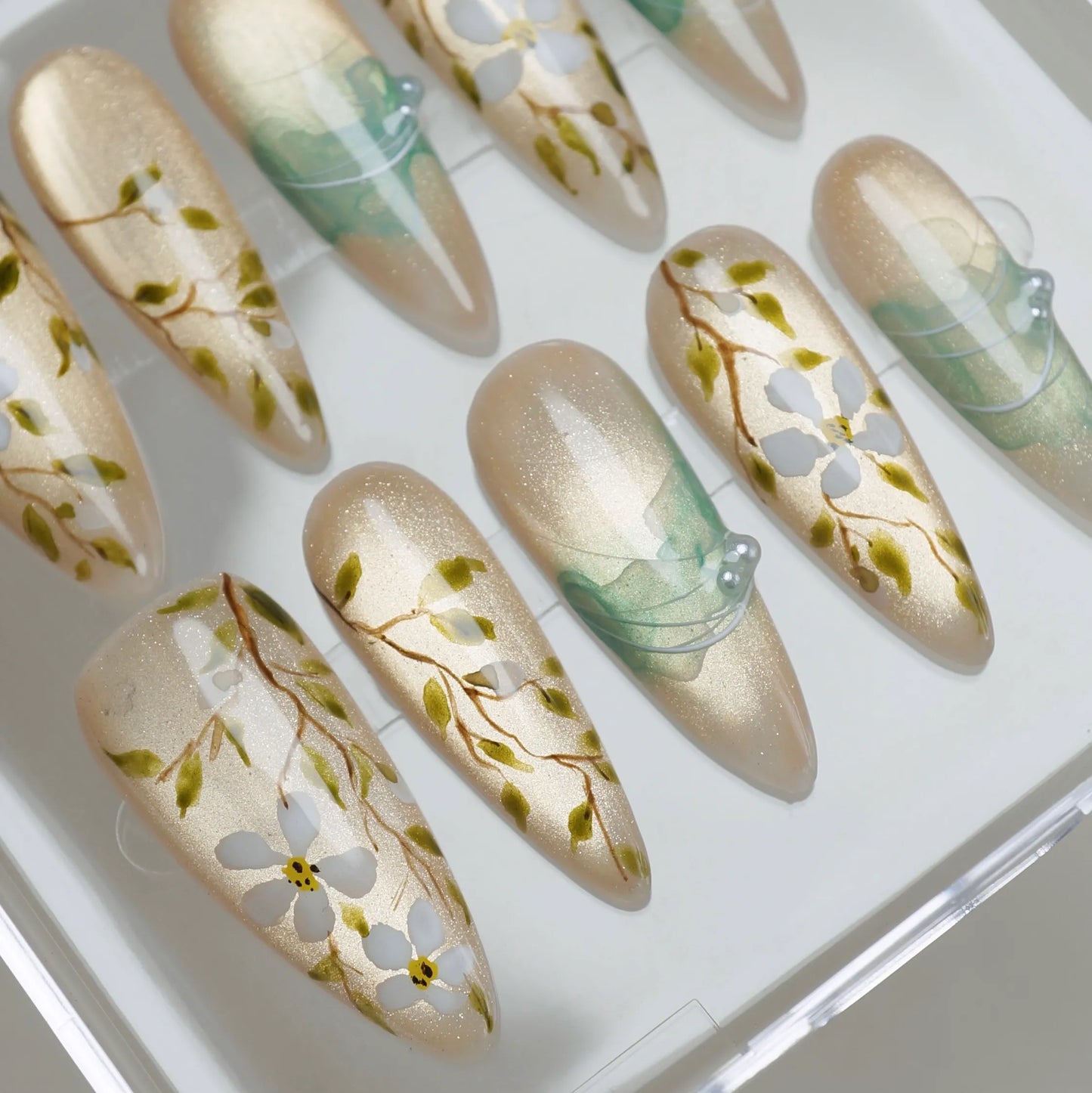 Orchard Veil close-up detail showing delicate white floral and vine detailing over a champagne shimmer gold base nail – Donailsart