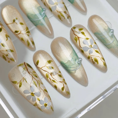 Orchard Veil close-up detail showing delicate white floral and vine detailing over a champagne shimmer gold base nail – Donailsart