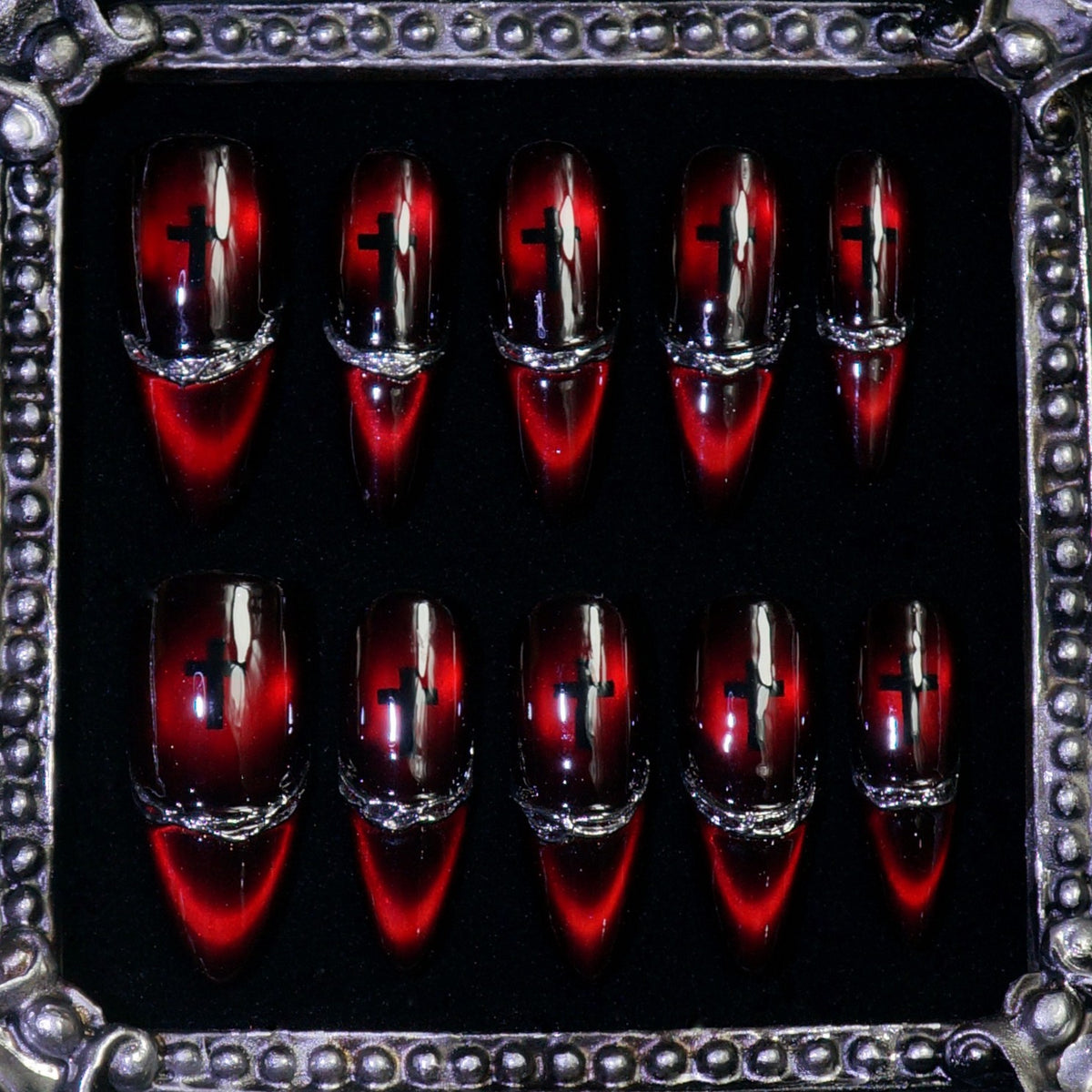 Sinner's Vow press-on nails: blood-red cat-eye stiletto nails with a black cross and silver chrome band