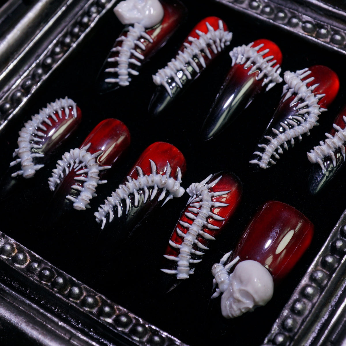 Human Centipede press-on nails, angled close-up of 3D bone spines and skulls