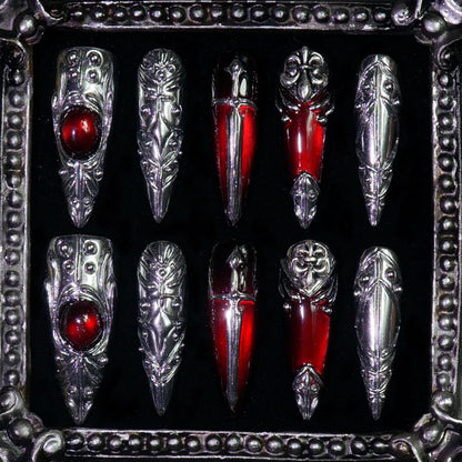 Blood Reliquary press-on nails: stiletto nails with sculpted 3D silver armor, red cat-eye gems and a dagger motif