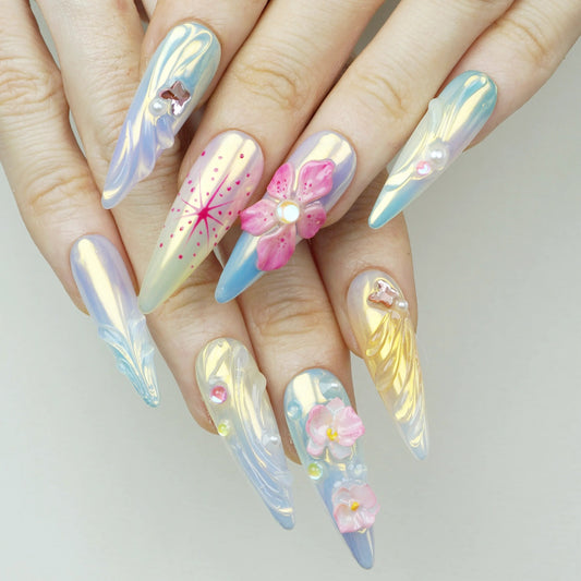 Flower Mirage press-on nails worn on hand model iridescent aurora stiletto nails with 3D pink flower charm hand-painted pink starburst firework art and holographic shimmer finish