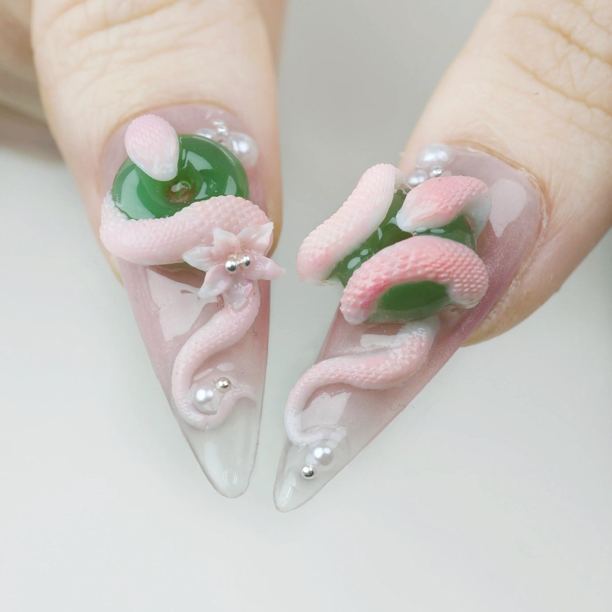 Nails with pink and green design on a white background