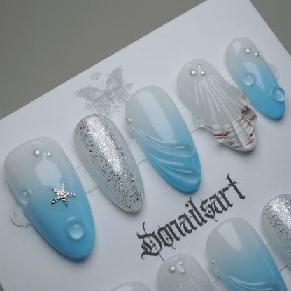 A30 | Blue Lagoon close-up detail showing sculpted shell texture and water droplet accents on a soft blue translucent nail – Donailsart