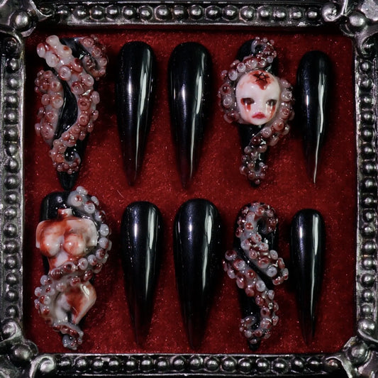 Haunted Doll press-on nails: glossy black nails with a 3D porcelain doll face and tentacle-like details