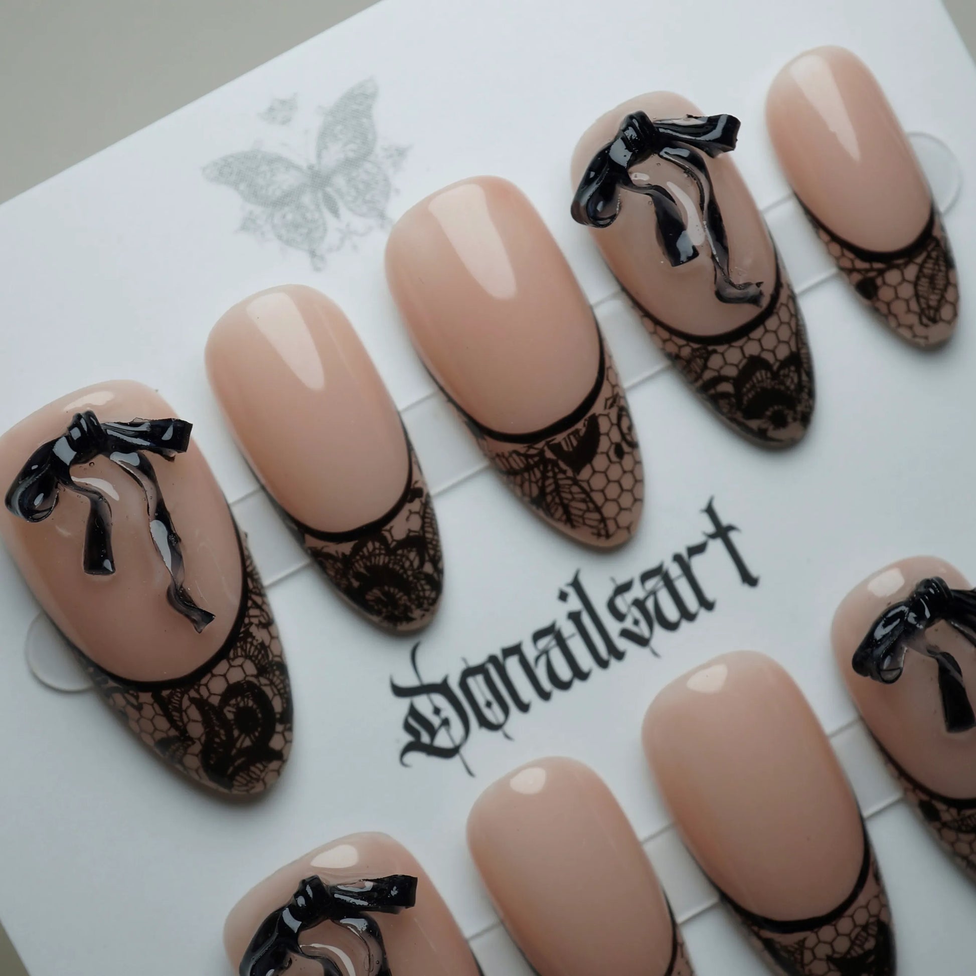 B4 | Sexy Lady close-up detail showing black lace-wrapped tips and sculpted ribbon accents on a sheer nude nail – Donailsart