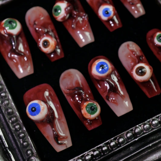 Blood Eyes press-on nails, angled close-up of 3D eyeballs on blood red
