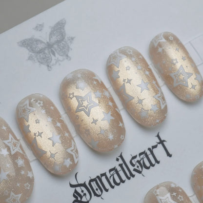 B5 | Ivory Lumen press-on nail set product view with subtle sheer ivory, warm gold shimmer, and star-pattern nail art by Donailsart