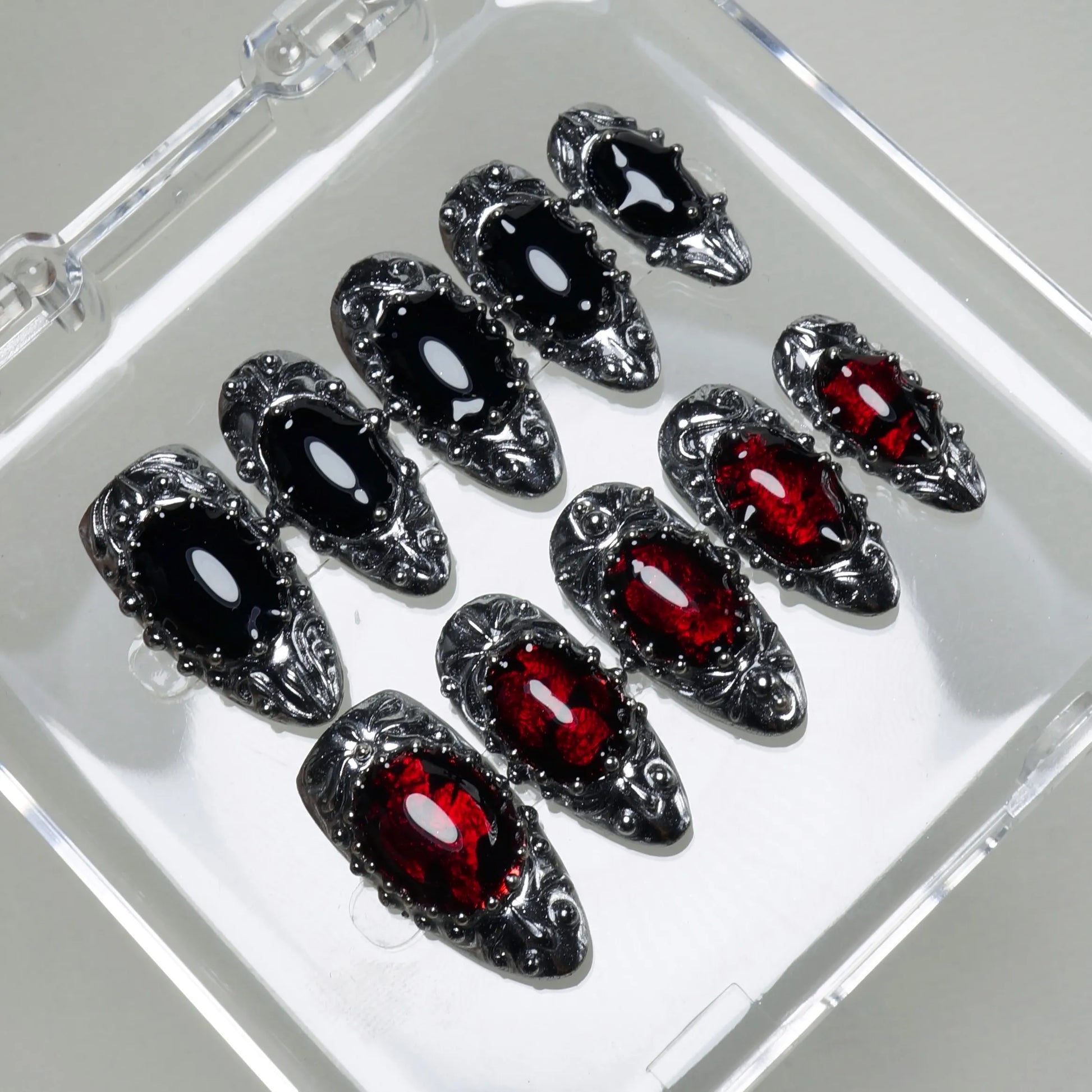 Elegant press-on nails featuring deep red and black glassy stones set in ornate silver baroque detailing