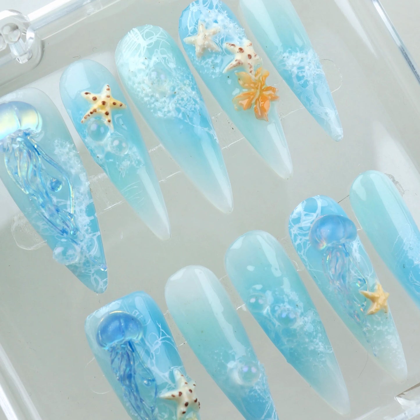 Summer nails with light aqua tones, floating sea creatures, and delicate marine details