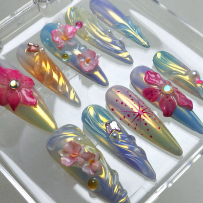 Summer flower nails in pastel yellow and blue hues with butterfly charms, starburst details, and crystal florals