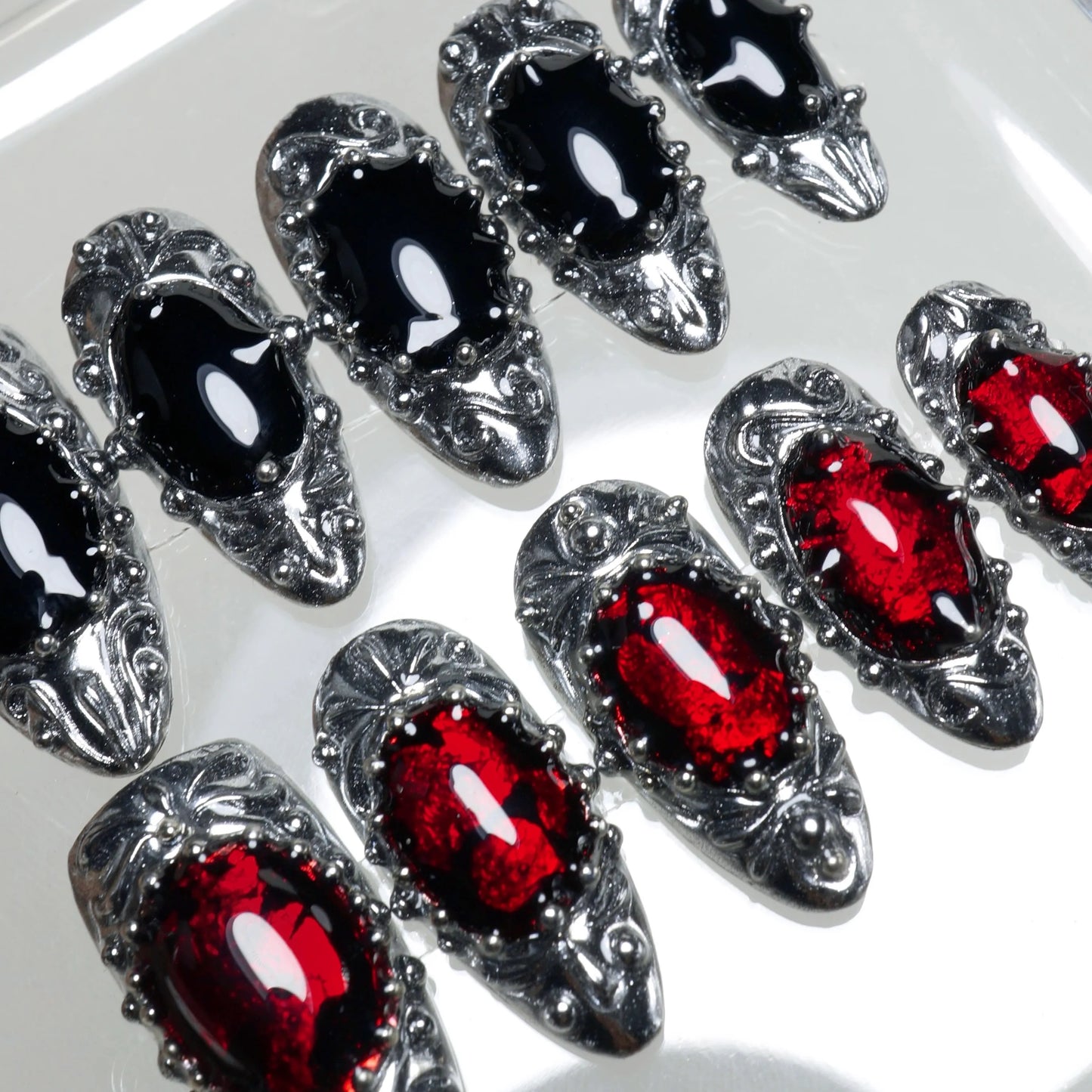 Gothic press-on nails with metallic sculpted frames, gemstone textures, and dark vampire-inspired palette