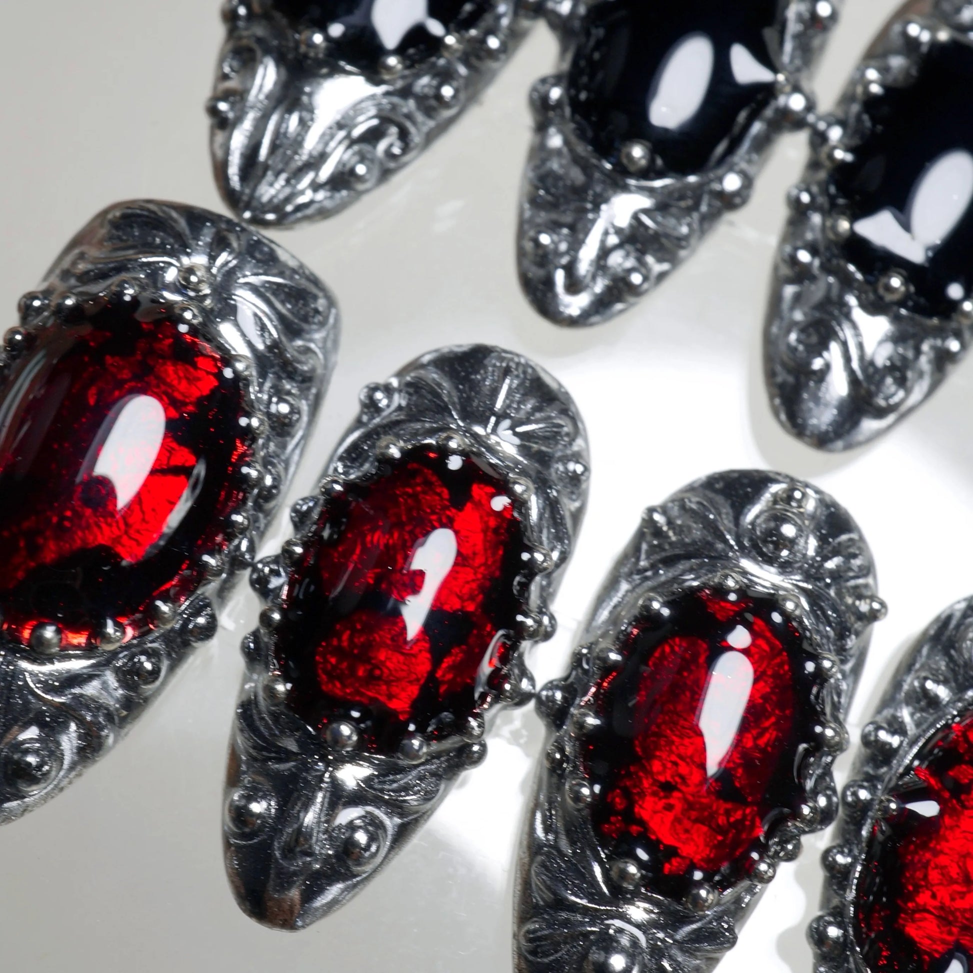 Press-on nails from Donailsart with vintage silver filigree and bold gemstone domes in red and black