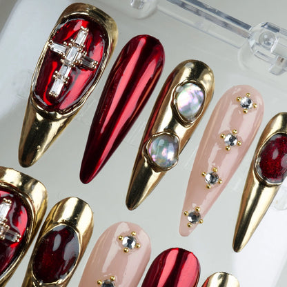 Striking press-on nails with gold and red chrome mix, nude rhinestone nails, and sculptural jewel settings