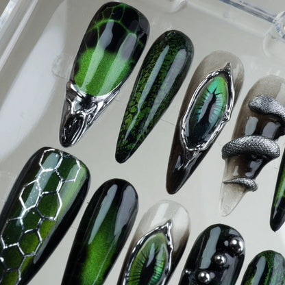 Fierce cat-eye nails design featuring chrome reptile eyes, metallic textures, and snake-inspired patterns