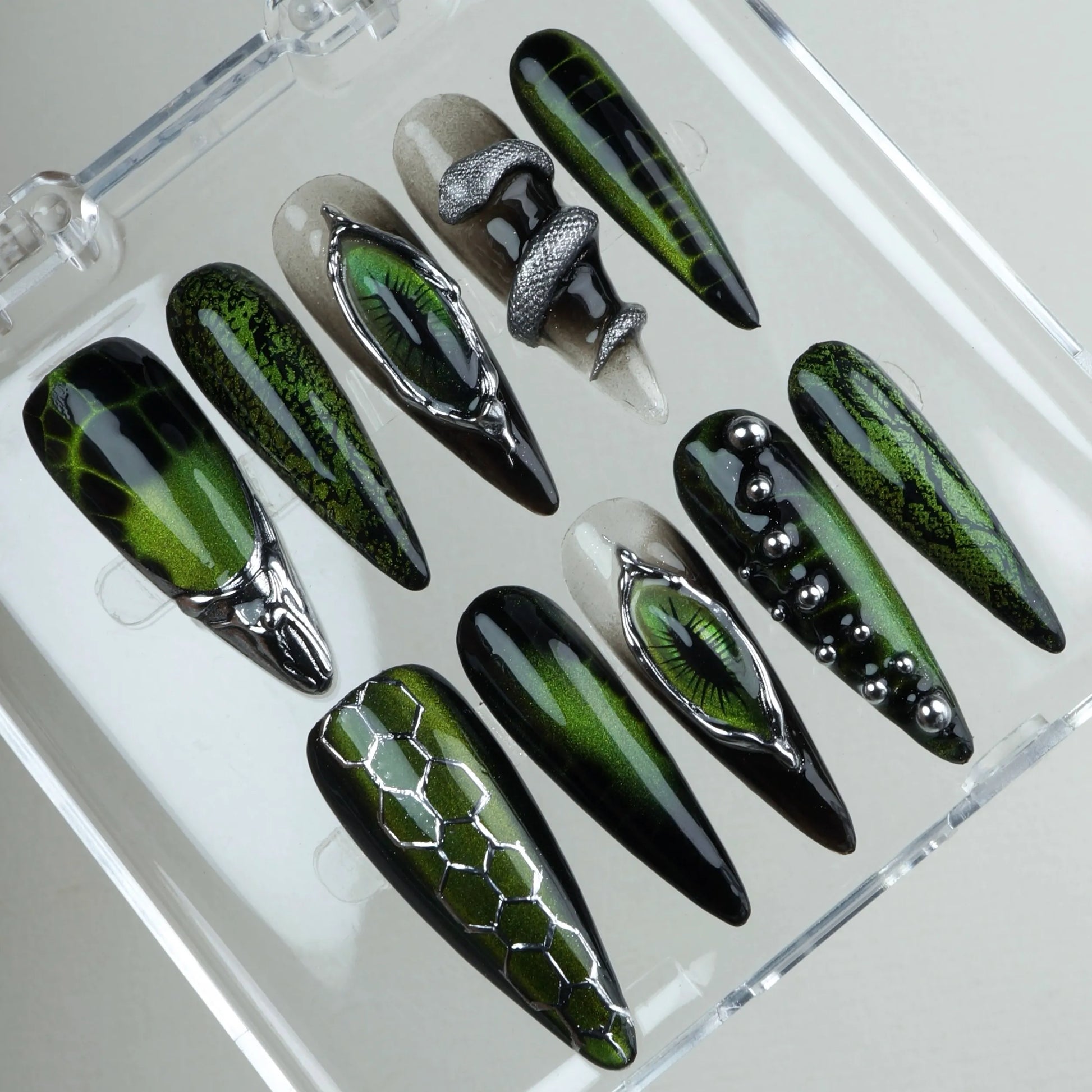 Fierce cat-eye nails design featuring chrome reptile eyes, metallic textures, and snake-inspired patterns