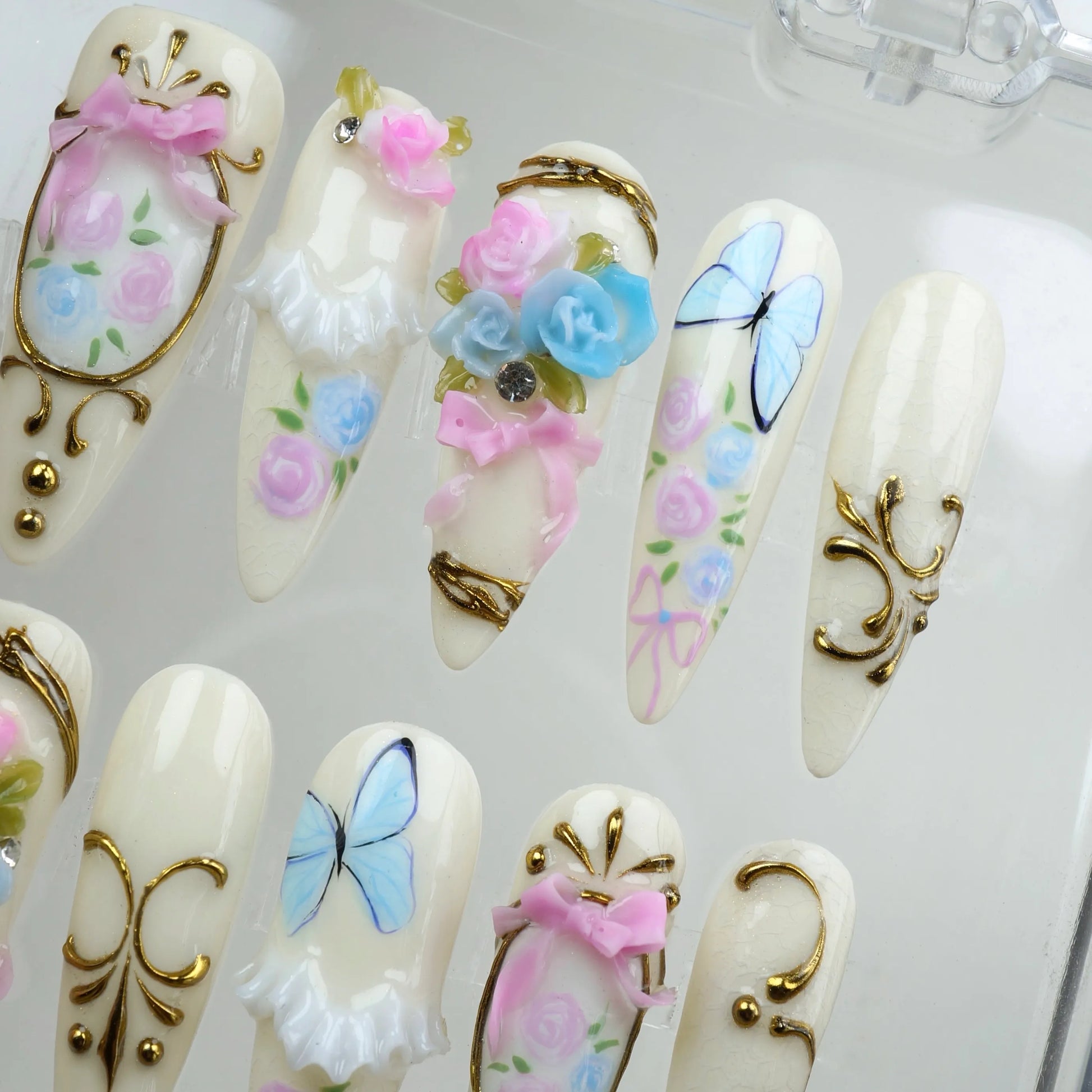 Donailsart birthday nails with pastel roses, blue butterflies, and ornate gold trims for a fairytale look