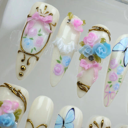 Regal birthday nails from Donailsart with hand-sculpted pink and blue roses, ribbon bows, and golden filigree