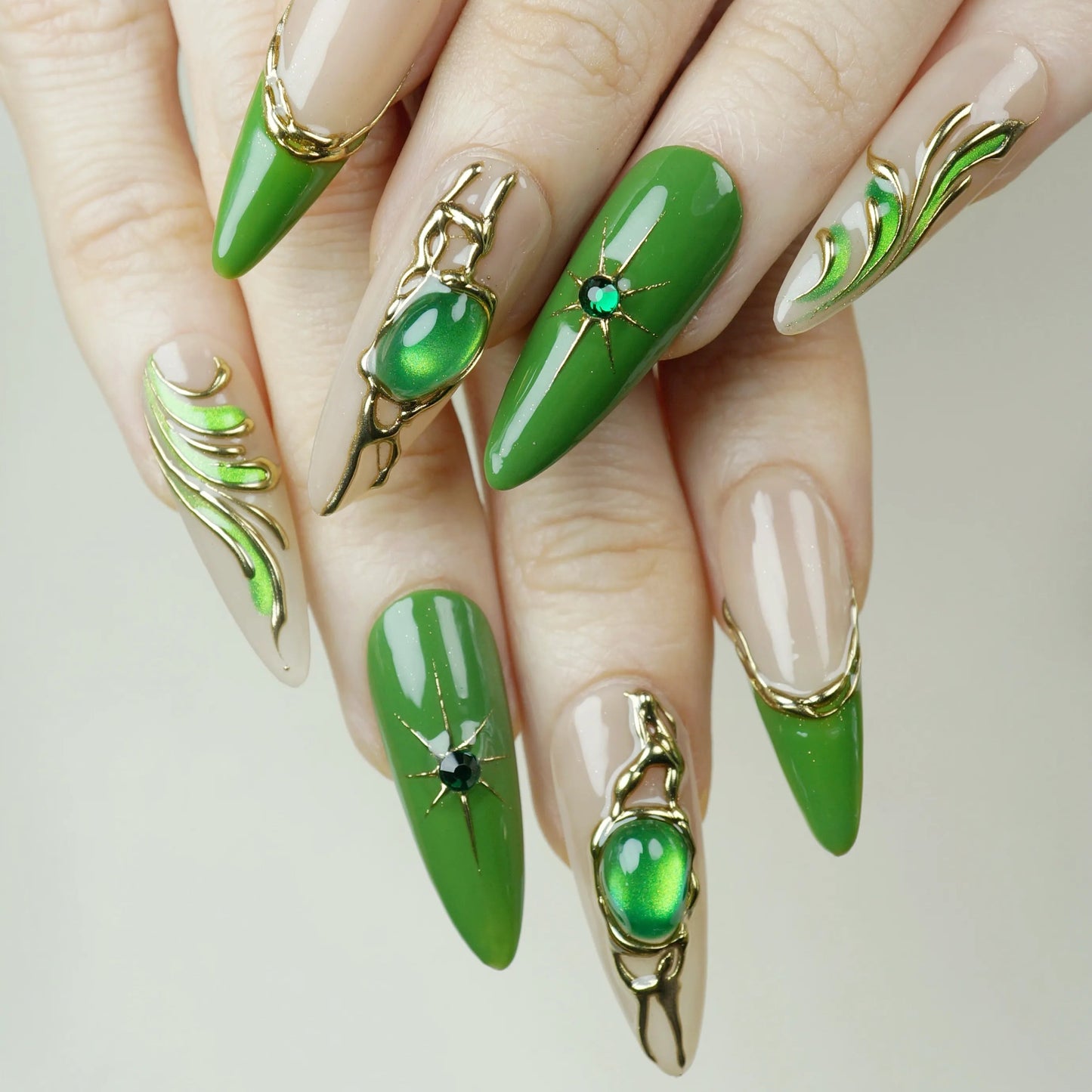 Close-up of hands with green nail art and decorative elements on a neutral background