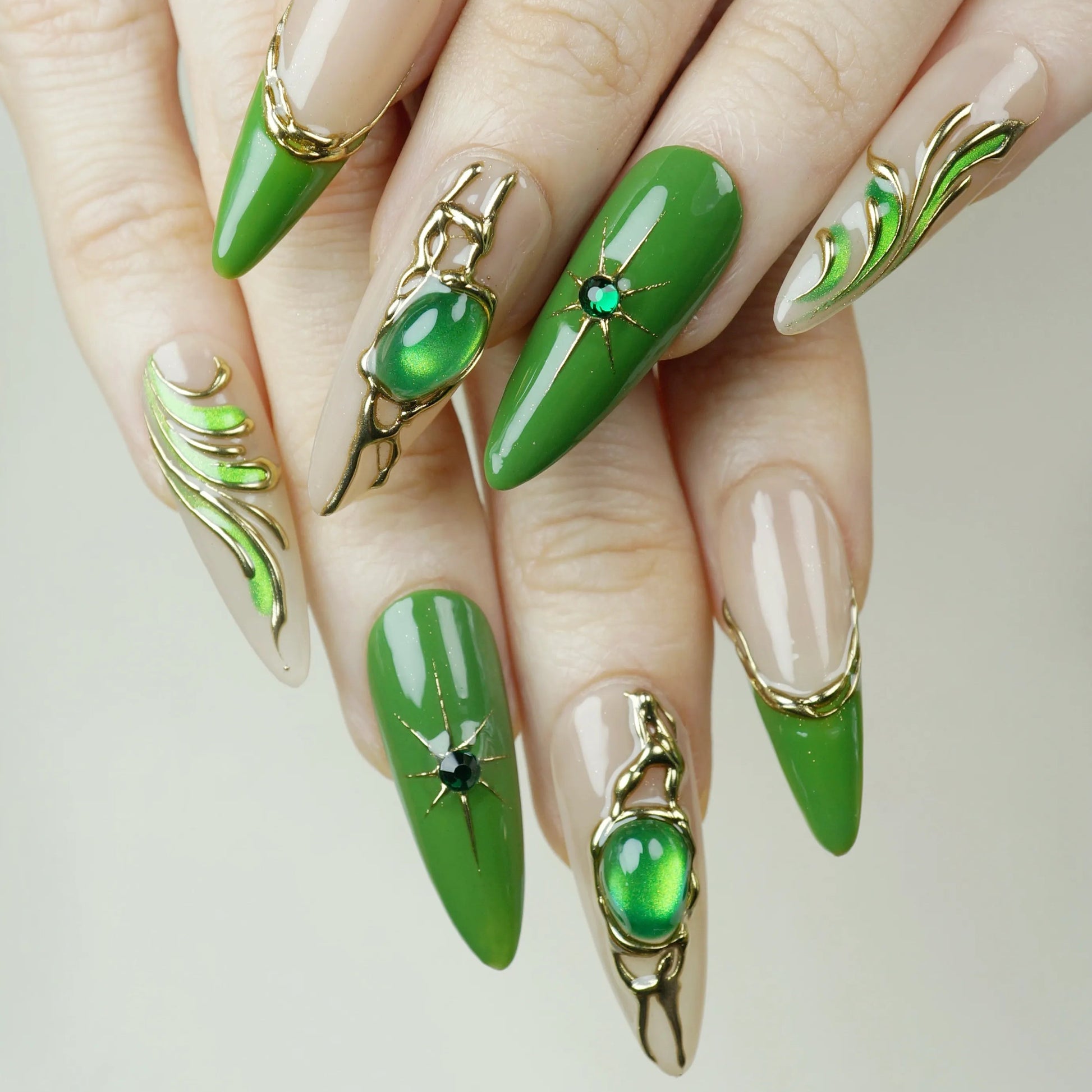 Close-up of hands with green nail art and decorative elements on a neutral background