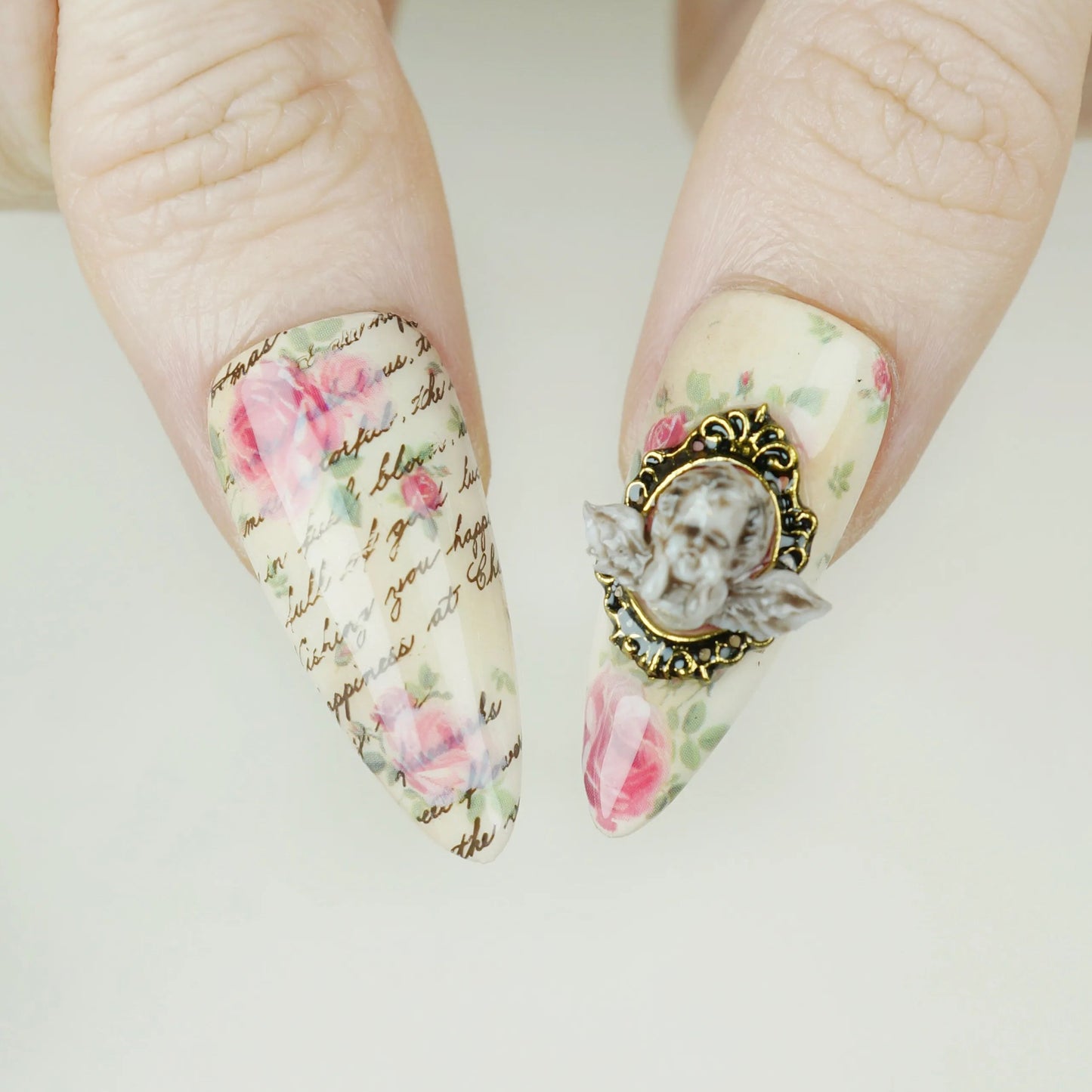 Cherub Relique close-up detail showing sculpted cherub cameo accent and gold frame on a blush shimmer nail – Donailsart