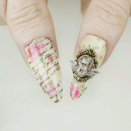 Cherub Relique close-up detail showing sculpted cherub cameo accent and gold frame on a blush shimmer nail – Donailsart