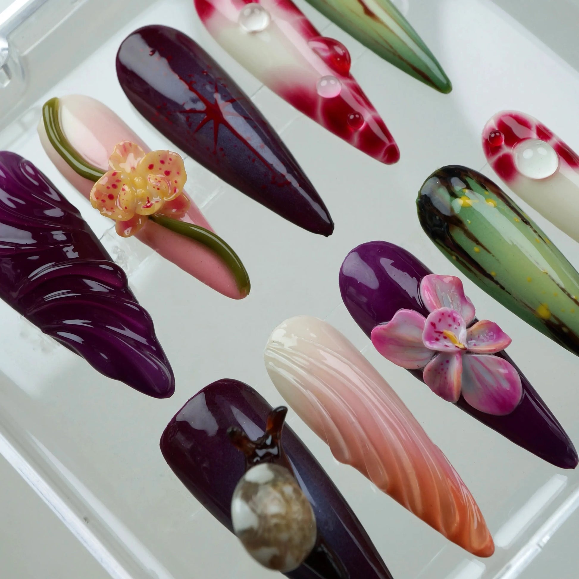 Artistic flower design nails with hand-painted leaves, orchids, and glossy gradients in a tropical garden palette