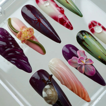 Artistic flower design nails with hand-painted leaves, orchids, and glossy gradients in a tropical garden palette