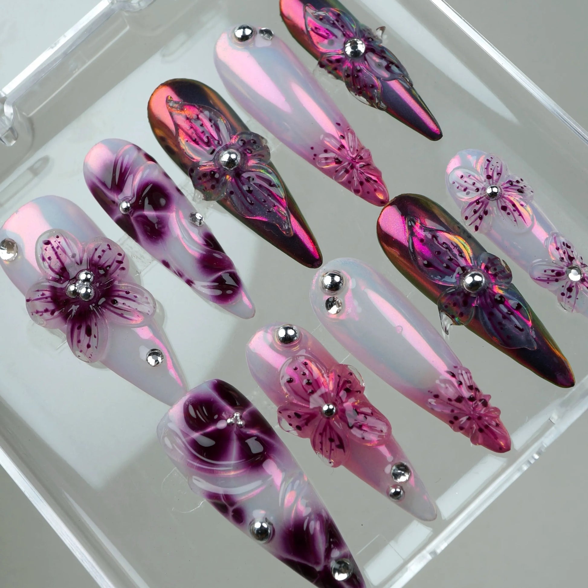 Sparkling flower design nails with layered petals, holographic shine, and silver bead accents for a chic vibe