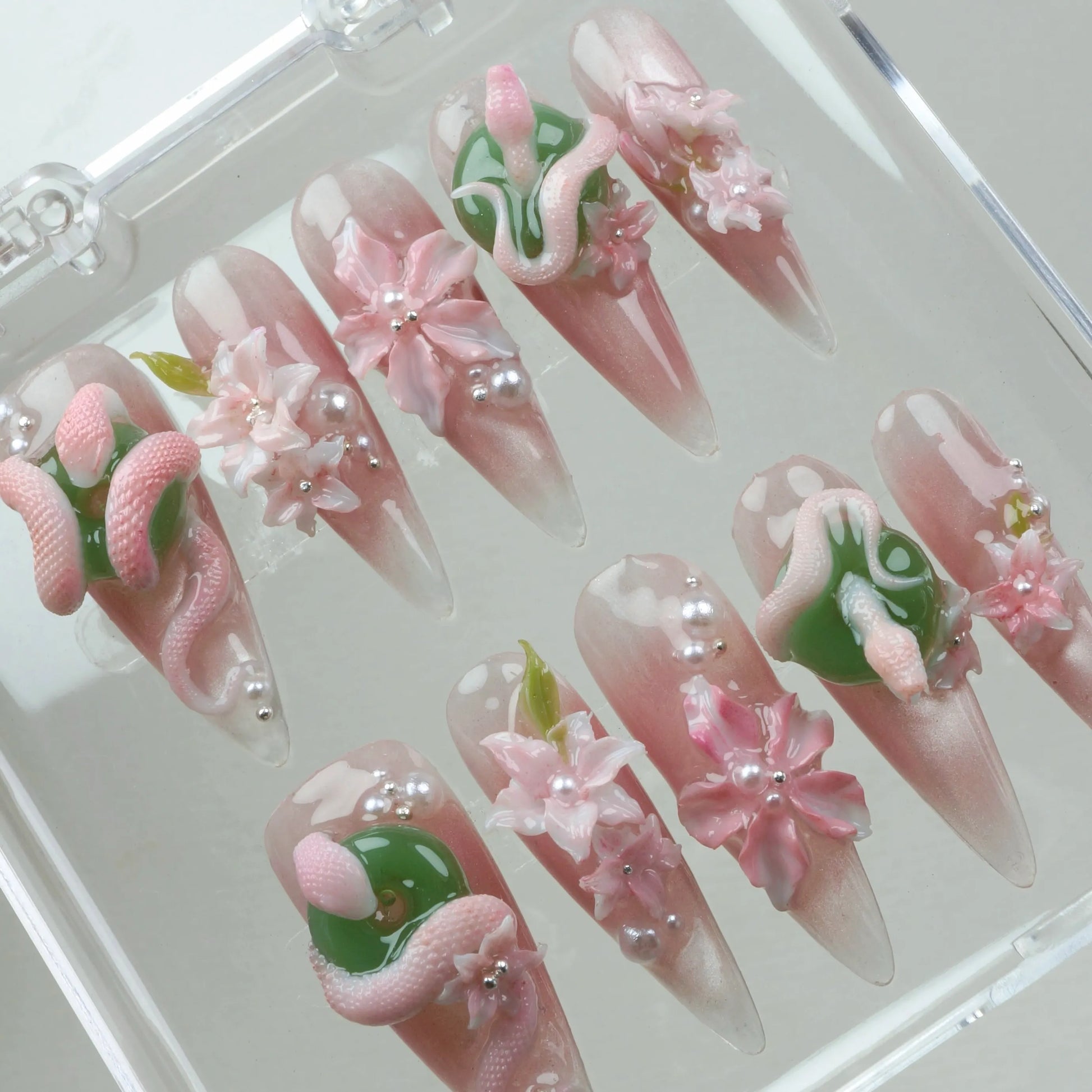 Fantasy-inspired flower design nails with pearl touches, blooming pink flowers, and textured snake shapes