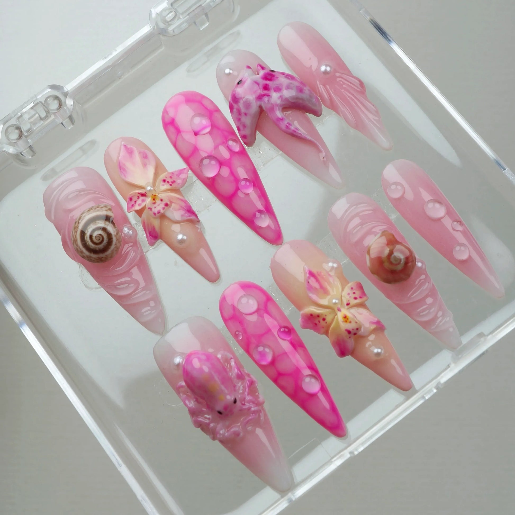 Pretty pink summer nails featuring ocean-inspired textures, realistic sea creatures, and tropical flower embellishments.