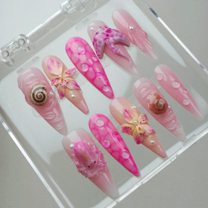 Pretty pink summer nails featuring ocean-inspired textures, realistic sea creatures, and tropical flower embellishments.