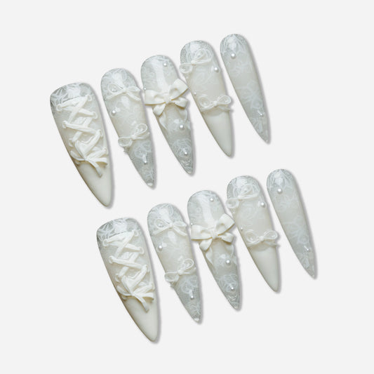 Ivory Keepsake press-on nail set by Donailsart – milky ivory nails with delicate lace patterns, glassy finish, sculpted bows, and tiny pearl accents