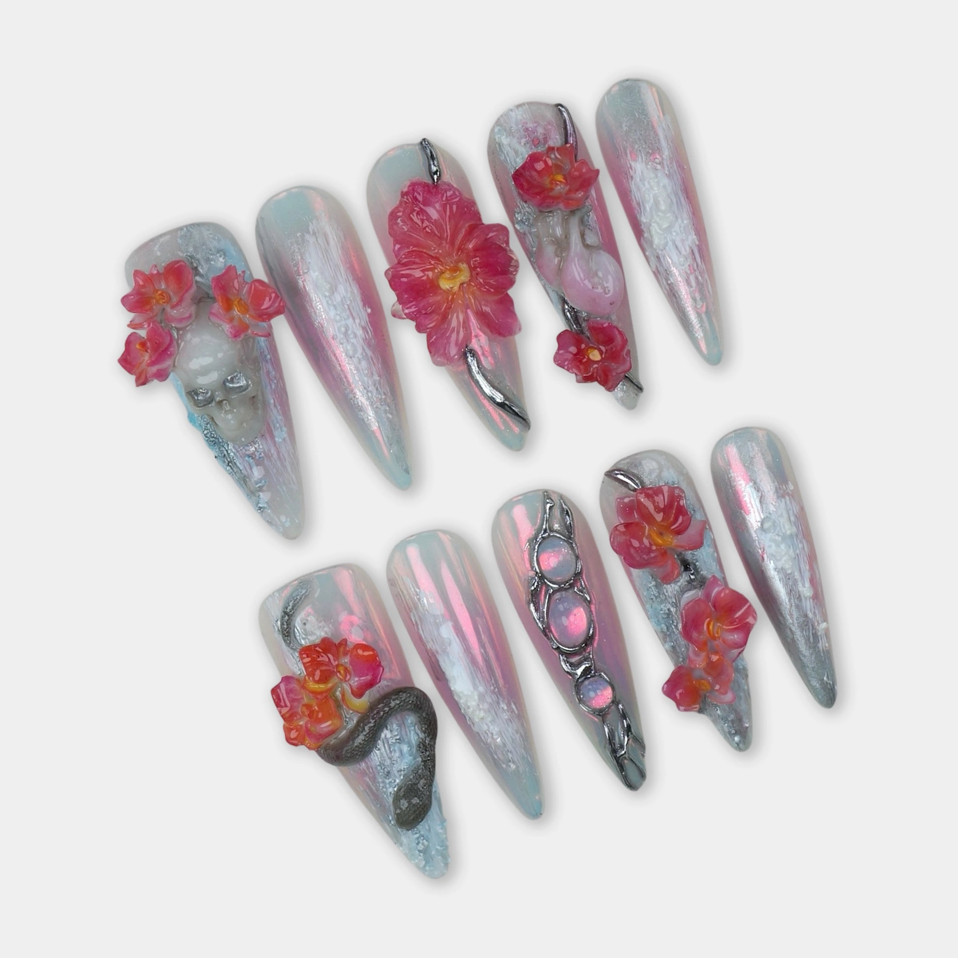 Summer nails art with iridescent chrome base, 3D pink flowers, sculpted skulls, snakes, and surreal elements by Donailsart