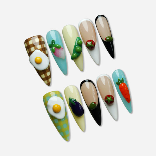 Picnic Plate press-on nail set by Donailsart – food-themed nail art with 3D fried eggs, tomatoes, carrots, peas, and eggplants on white background