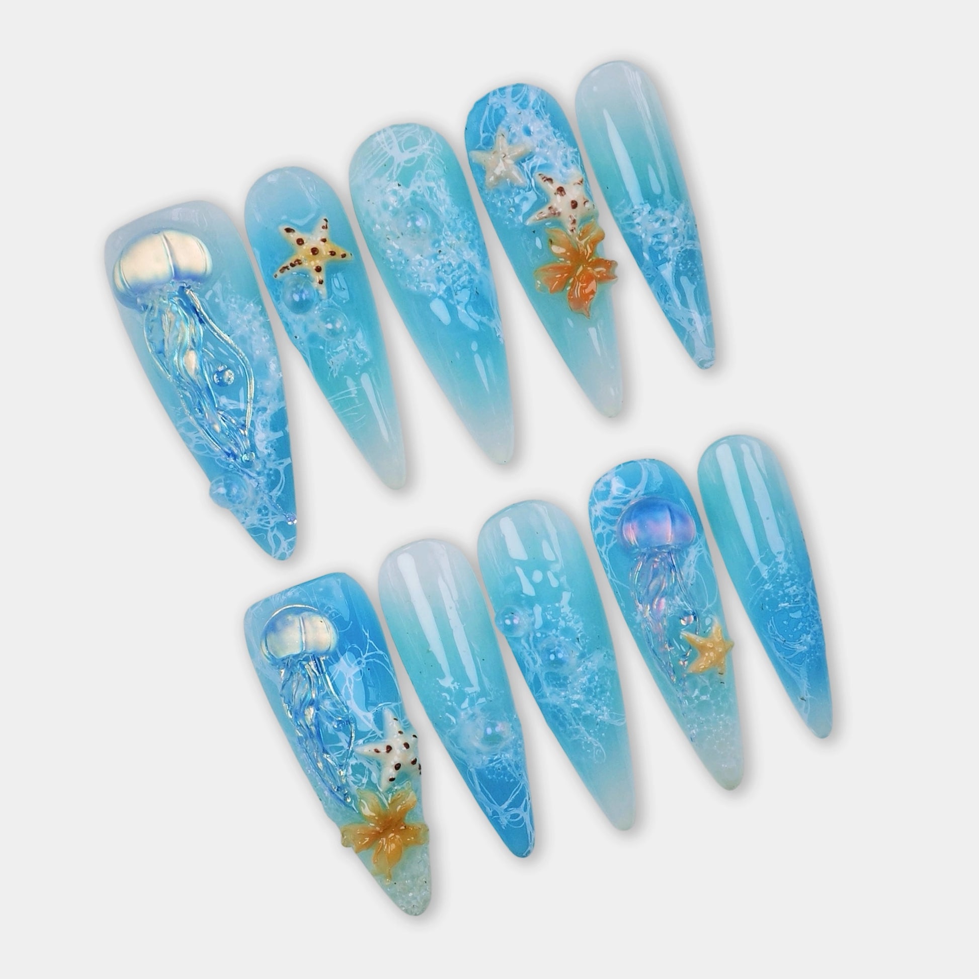 Summer nails with translucent blue ocean gradients, 3D jellyfish, starfish charms, and seafoam textures by Donailsart