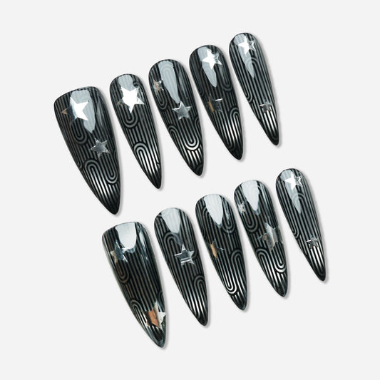 Stellar Maze press-on nail set by Donailsart – glossy black nails with silver metallic maze-like linework and star accents inspired by retro space-age patterns