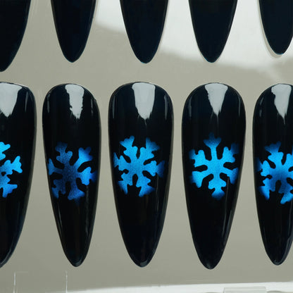 Black nail extensions with blue snowflake designs on a clear background