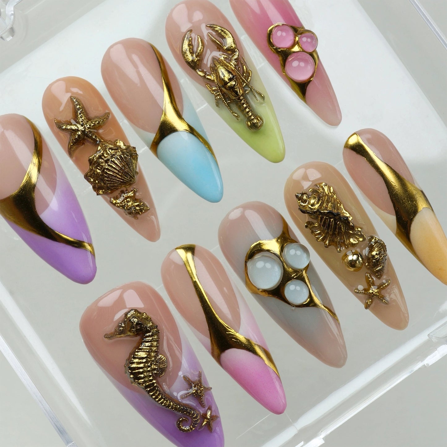Bold ocean-themed press-on nails from Donailsart with gold sea creature charms and soft gradient tips in purple, pink, blue, and peach