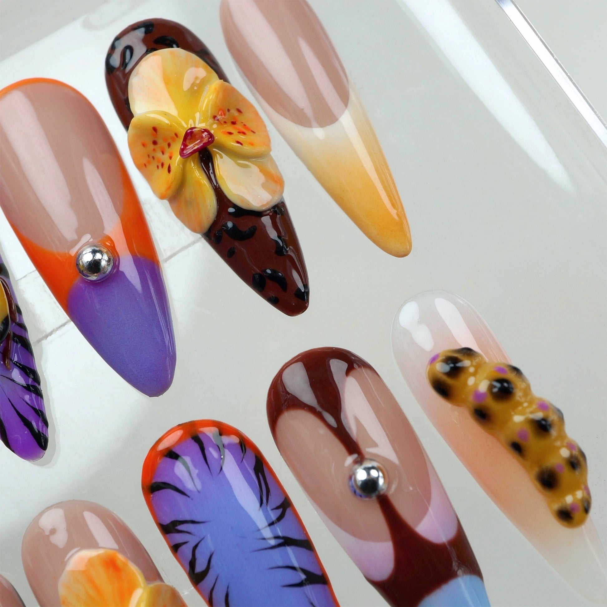 High-fashion press-on nails by Donailsart with modern shapes, chrome studs, and tropical jungle-inspired motifs