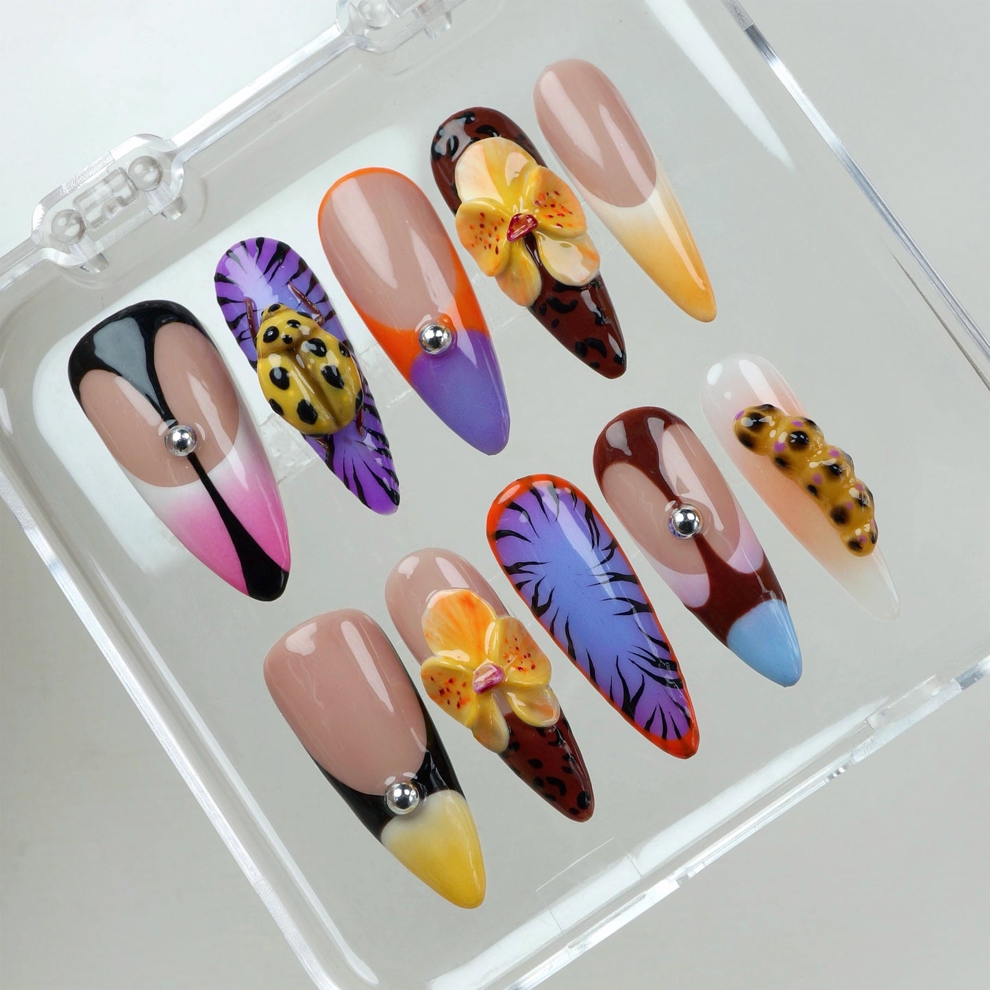 Press-on nails by Donailsart with hand-painted tropical petals, bold color blocking, and 3D orchid accents