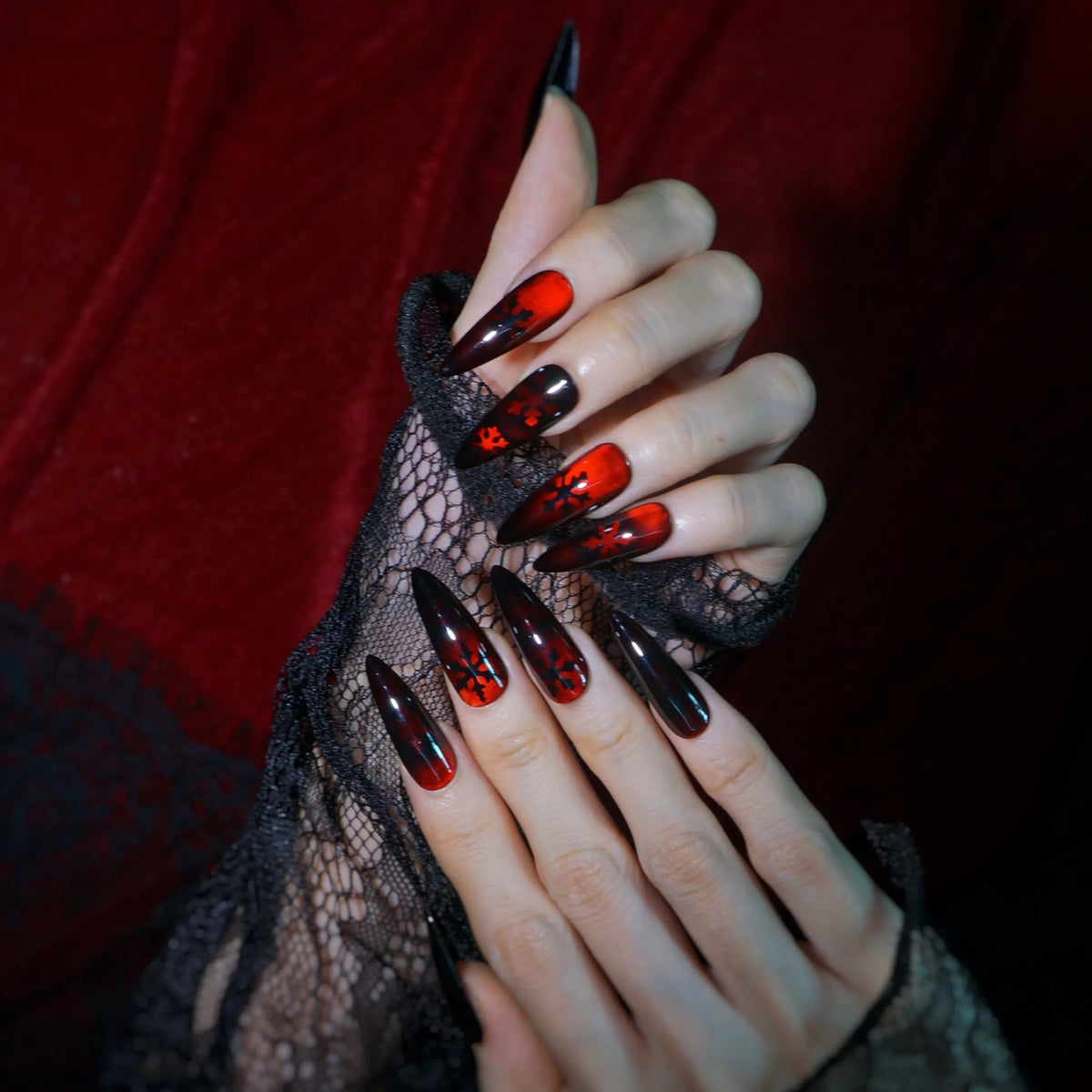 Crimson Frost blood red and black stiletto press-on nails with snowflake art, full set on hand