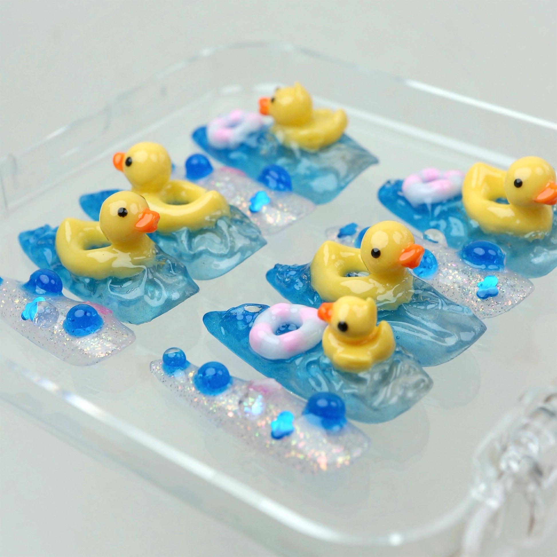 Playful funny nail art set with blue water textures, glitter accents, and tiny 3D duck figures