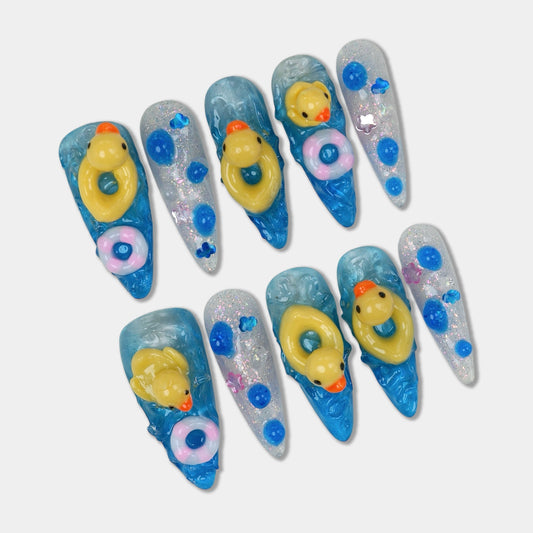 Funny nail design featuring 3D rubber ducks and colorful float rings on glittery blue water-effect nails