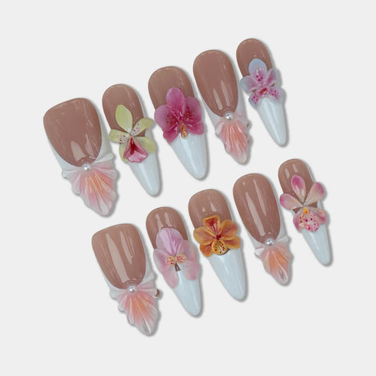 Flower nails with pastel 3D blossoms, white tips, and seashell-inspired accents on a nude base