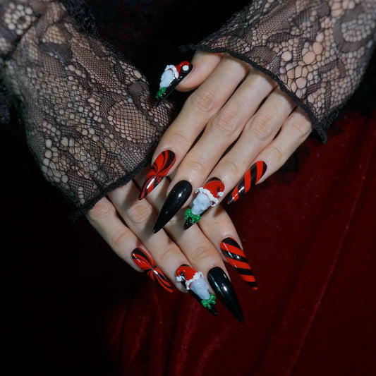Skully Claus creepmas stiletto press-on nails with candy stripes and Santa hat skull charms on hands