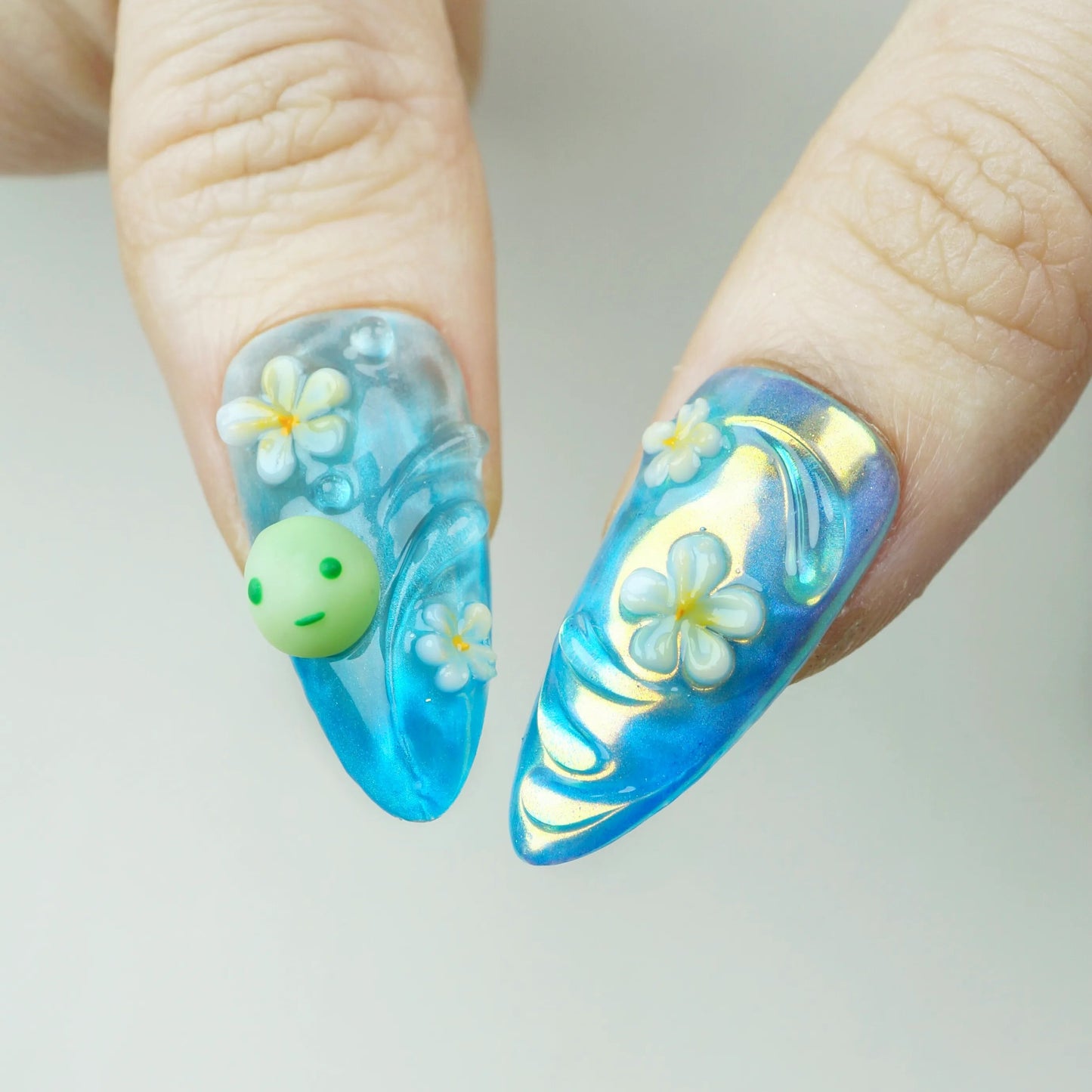 Nails with blue and white floral design on a plain background