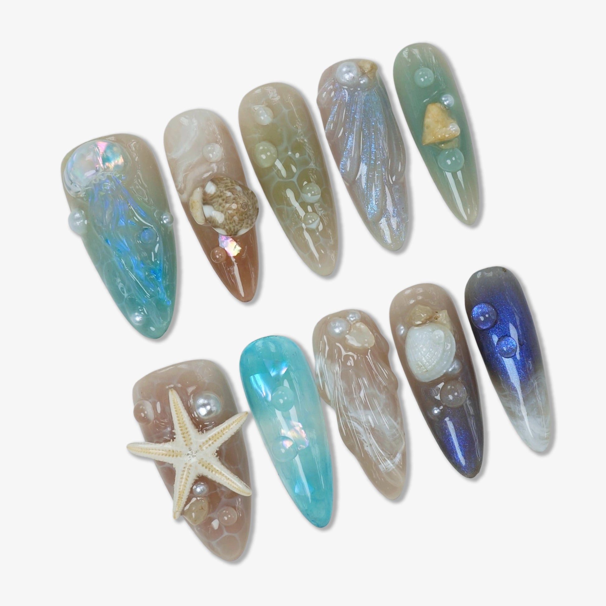 Ocean-inspired summer nails with seashells, pearls, and starfish designs in soft pastel and iridescent tones.